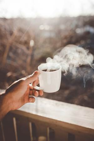 image of someone holding a hot coffee mug outside